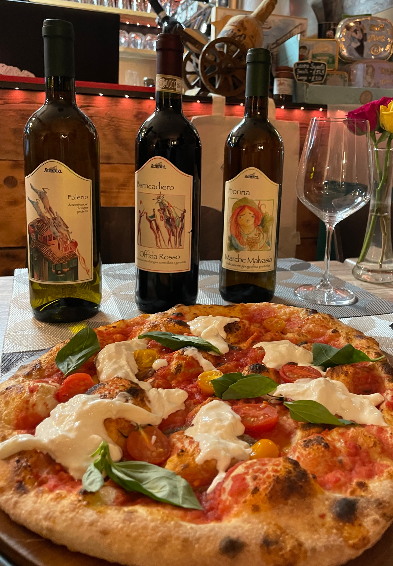 Romana pizza topped with tomatoes, basil and creamy cheese, served with Aurora wine bottles