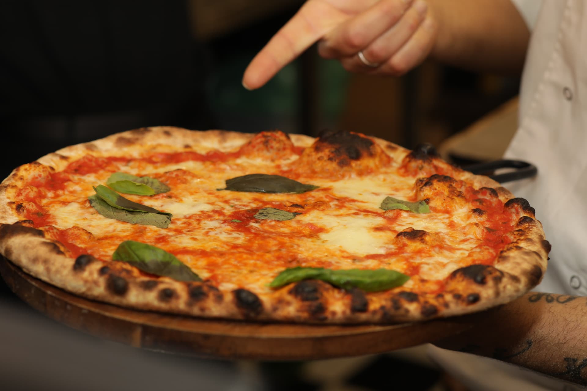 Margherita Romana pizza held on a wooden peel at History Pizzeria